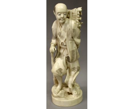 A SIGNED JAPANESE MEIJI PERIOD IVORY OKIMONO OF A WOODSMAN, standing on rockwork with a hawk at his feet, the man holding an 