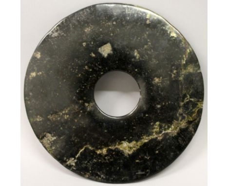 A LARGE CHINESE NEOLITHIC PERIOD JADE BI DISC, the stone predominantly black in tone, 8.3in diameter.