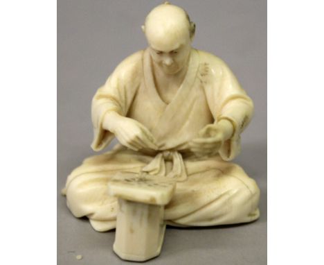 A SMALL SIGNED JAPANESE MEIJI PERIOD IVORY OKIMONO, of a man seated before a game board with small playing sticks in his hand