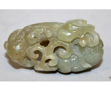 A 19TH/20TH CENTURY CHINESE CELADON JADE PIERCED CARVING, in the form of a chilong next to fruit and lingzhi fungus, 2in wide