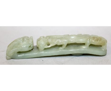 A CHINESE CELADON JADE BELT HOOK, the stem pierced and carved in high relief with a sinuous chilong, the hook in the form of 