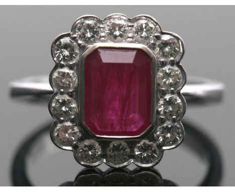 18ct white gold, ruby and diamond cluster ring, the rectangular cushion cut ruby bezel set and raised within a 14 diamond sur