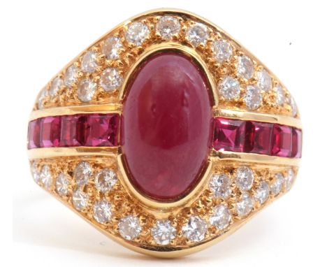 18ct gold ruby and diamond cluster ring, the oval shaped panel centring a cabochon ruby, flanked either side by square calibr