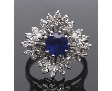 Sapphire and diamond cluster ring, a snowflake design centring a round cut faceted sapphire (7mm diam) within a small diamond