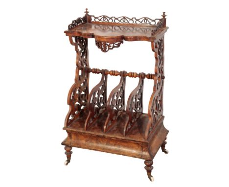 A VICTORIAN WALNUT CANTEBURY WHATNOT with four divisions, scrolling sides above a long drawer on ceramic castors, Height 98cm