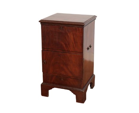 A GEORGE III MAHOGANY BEDSIDE COMMODE with a hinged lid containing a fitted interior, above two graduating doors on bracket f