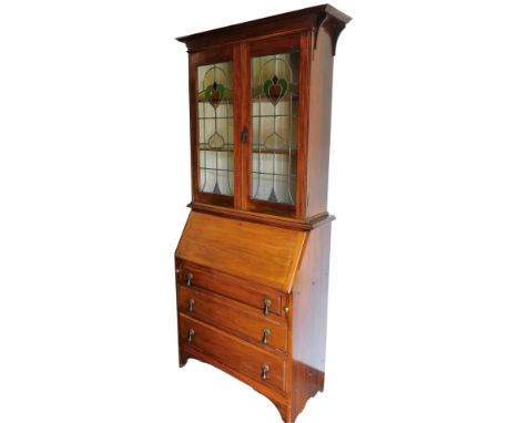 A Victorian Art Nouveau mahogany bureau bookcase, the outswept pediment over a pair of leaded stained glass doors, enclosing 