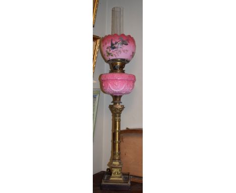 Oil lamp having a pink glass reservoir with decoration in relief, brass classical column on a stepped square foot and with a 
