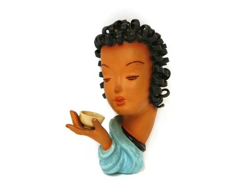 A Goldscheider wall mask, of a lady holding a cup, wearing a turquoise top, faint printed mark, 22cm high Provenance: The Cra