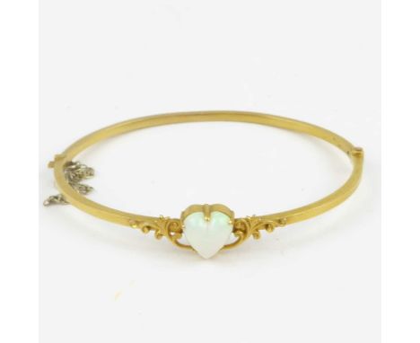 An early 20th century 15ct gold hinged bracelet with claw set heart-shaped cut opal with flashes of green, red and white, wit