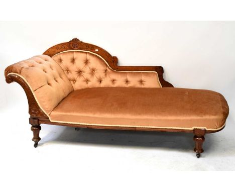 A Victorian carved mahogany chaise longue with button upholstered scroll arm and back, raised on turned supports to castors.
