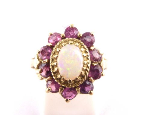 An 9ct gold opal and pink topaz set cluster ring, the central claw set white opal with flashes of green, blue and red, within