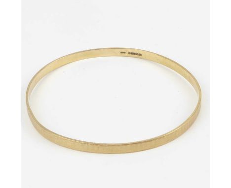 A 9ct gold bangle with engine turned decoration, internal diameter approx. 7.8cm, approx. 14.8g.