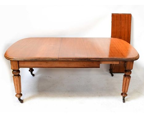 A Victorian mahogany wind-out dining table with two additional leaves, raised on substantial reeded supports to castors, when