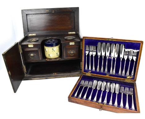 A vintage oak smokers' cabinet with pottery mixing bowls, two small plated dishes, above two drawers, each drawer with title 
