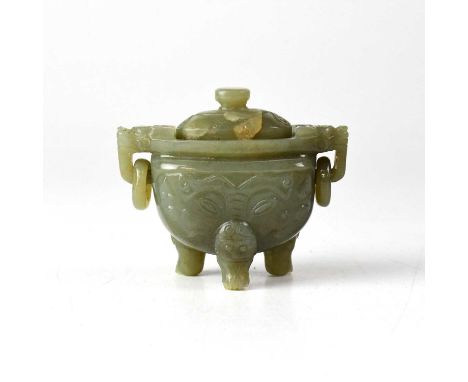 A Chinese jade twin-handled lidded vessel, the ring handles held in the mouths of beasts, the body carved with a face to both