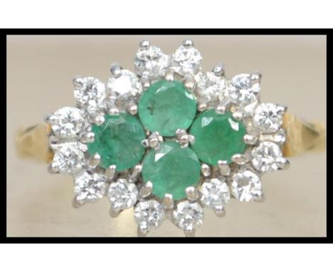 An 18ct gold, diamond and emerald ladies cluster ring having 4 central round cut emeralds surrounded by approximately 16 diam