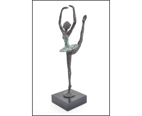 A decorative vintage cold painted cast metal sculpture of a young ballet dancer raised on a single leg in a classic ballet po