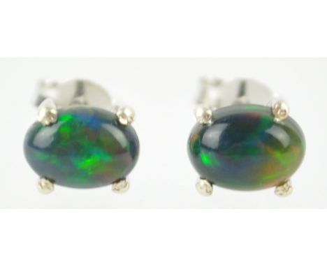 A white metal single stone pair of stud earrings. Each set with an oval cabochon cut black welo opal. Post and scroll fitting