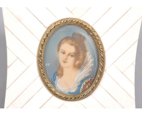 An oval miniature portrait of a bust-length lady in historical revival dress, in gilt metal and chevron bone cushion-shaped f