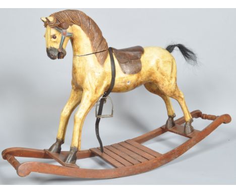 A 20th century carved rocking horse. The horse having a carved mane and face with leather saddle and metal stirrups, all bein