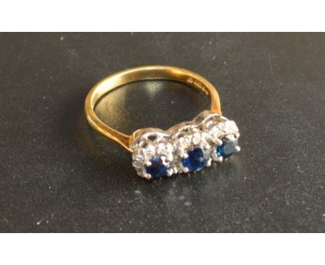 An 18 Carat Gold Sapphire and Diamond Triple Cluster Ring set with three sapphires surrounded by diamonds within a pierced se