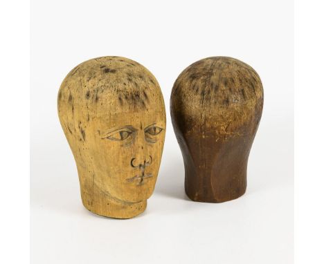 2 Perückenköpfe aus Holz.             H 25 und 24 cm.             Heller Kopf mit geschnitzten Gesichtszügen, dunkler Kopf nu