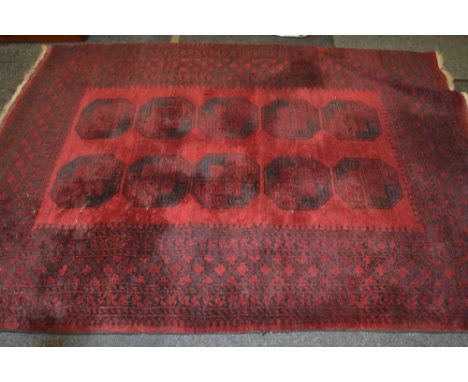 An Afghan woollen carpet,  with ten reserves on a red ground,. geometrical border, 242cm x 171cm