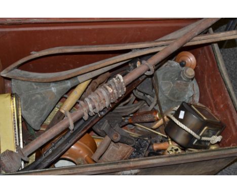 A vintage metal travelling trunk containing;  lamp, trivets, flat irons, shoemakers tools; copper kettle; etc