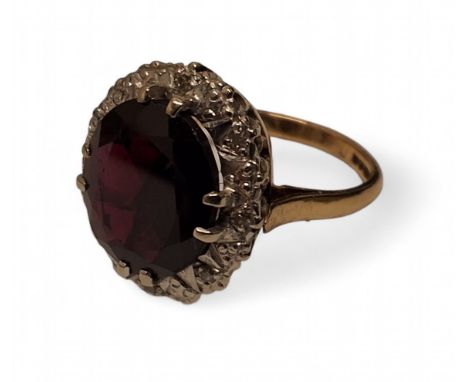 A 9ct gold halo dress ring, set with a oval red stone 9large inclusion), diamond chip halo, stamped 375, size K, 4.2g gross 