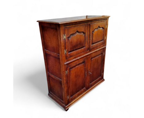 A Cumpers of Salsbury golden oak drinks cabinet model No.SC32, arched fielded panelled cupboard doors revealing glass shelvin