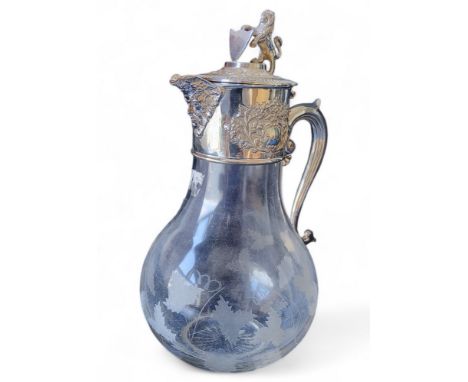 A silver plated claret jug, rampant lion and shield finial,&nbsp; hinged cover, green man spout,&nbsp; &nbsp;etched with grap