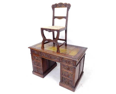 An Antique stained oak pedestal kneehole writing desk, with green leather skiver and relief carved lion decoration, W122cm, H