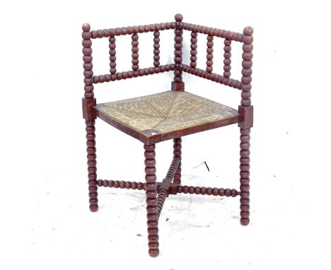 An Antique rush-seated bobbin turned corner chair 
