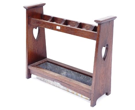 An Art and Crafts oak stick stand in the manner of Liberty's, with pierced heart cut-outs and drip tray, L80cm, H70cm, D28cm 