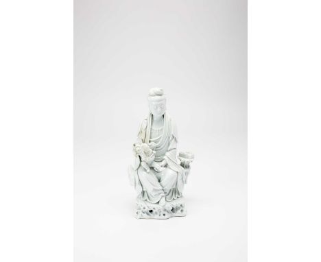 A CHINESE BLANC DE CHINE FIGURE OF GUANYINLATE QING DYNASTYThe Goddess sits with a serene expression holding a child in her l