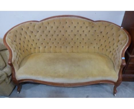 An early 20th century walnut and deep buttoned sofa with shaped back, on cabriole legs with ceramic castors. 72' wide