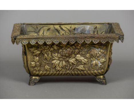 A 19th century Japanese repousse decorated planter
The lappet set border above panels decorated with lilies, chrysanthemums a