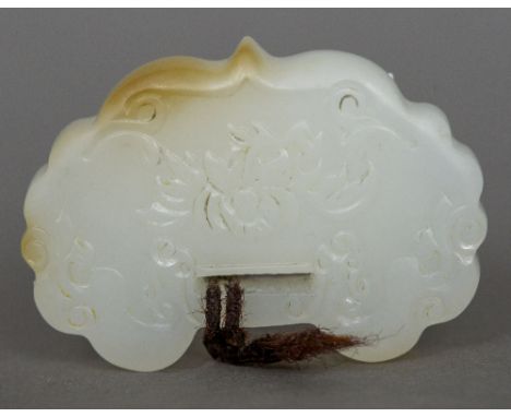 A Chinese carved white jade pendant
Of serpentine form, worked with floral sprays.  4 cm wide. CONDITION REPORTS: Generally i