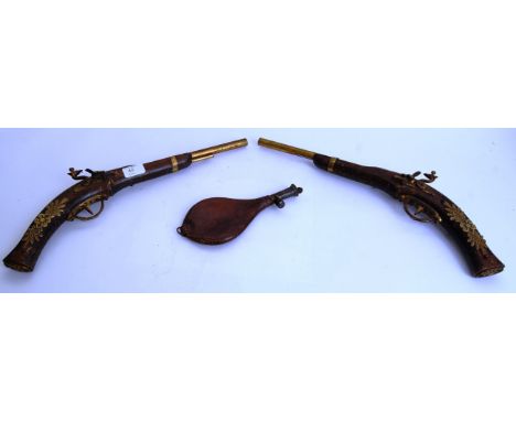 ARMS: A pair of reproduction decorative flintlock pistols, each with brass decorated barrels, along with an original powder f