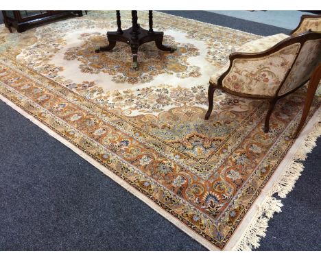 A 20th Century carpet with a foliate rust coloured medallion upon the cream ground, bordered by floral shoots and a repeat pa