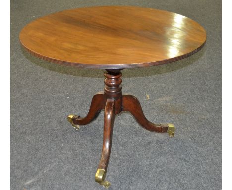 A 19th Century mahogany snap-top supper table of circular form, with a turned pedestal and tripod base with applied brass cas