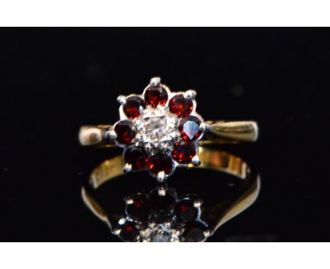 An 18ct garnet and diamond cluster ring, central illusion set diamond within an eight stone garnet surround, ring size K. 