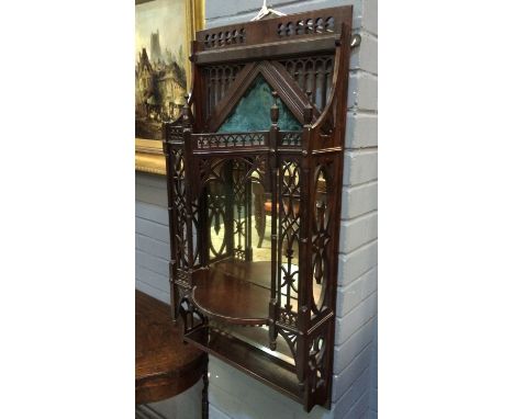 A 19th Century mahogany wall mounted shelf in the Gothic taste with pierced fret work frame and shelves before a mirror back.