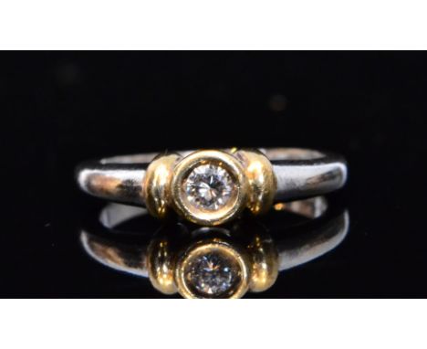 An 18ct white and yellow gold diamond solitaire ring, collar set brilliant cut stone flanked by yellow gold highlights to sho