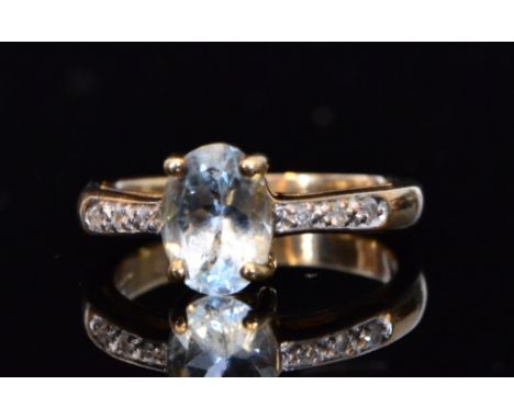 A modern 9ct hallmarked aquamarine and diamond ring, central oval claw set aquamarine flanked by three diamonds to each shoul