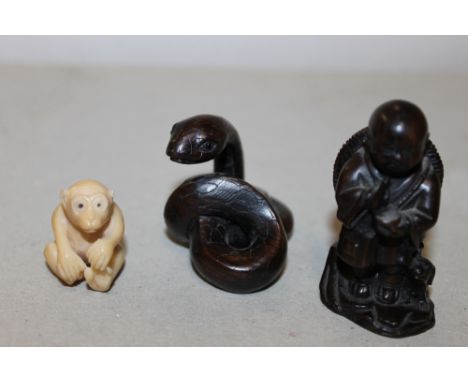 A SMALL CARVED NETSUKE IN THE FORM OF A MONKEY, H 2.7 cm, together with two carved wooden netsukes in the form of a serpent, 