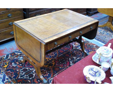 An early 19th century cross-banded satinwood sofa table, the top with rounded drop ends over a pair of frieze drawers opposin