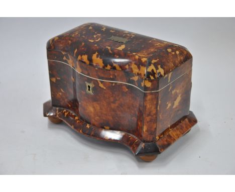 A serpentine tortoiseshell tea caddy with brass cartouches, 20 cm wide