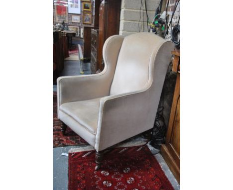 A late Victorian upholstered wing back armchair raised on turned mahogany front legs, the legs stamped marks on leg G or CVS 